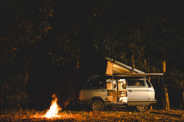 camping with camper van and fire at night under the tree in the forest mountain field